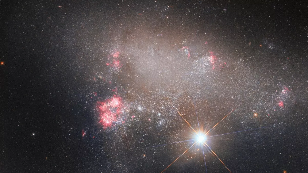 Telescópio Hubble captura estrela ofuscando uma enorme galáxia